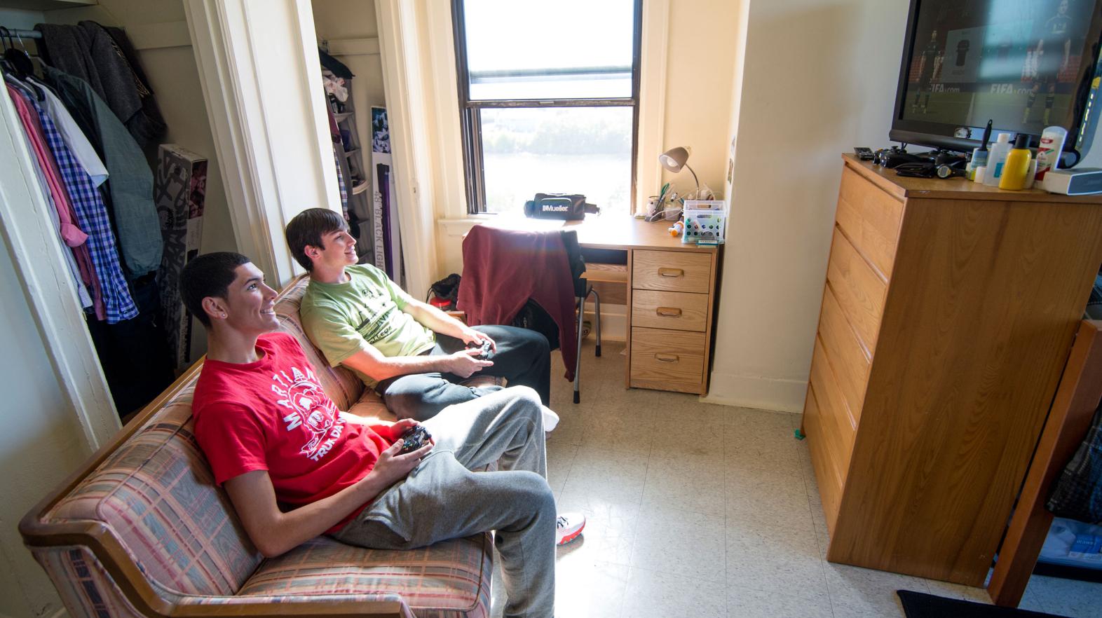 Two students play video games in their Alumni Hall dorm room.