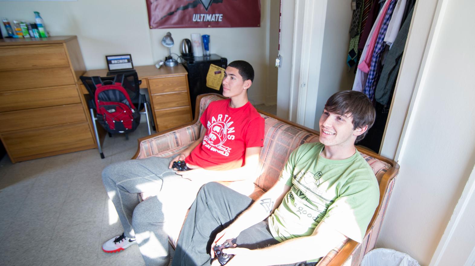 Two students play video games in their Alumni Hall dorm room.