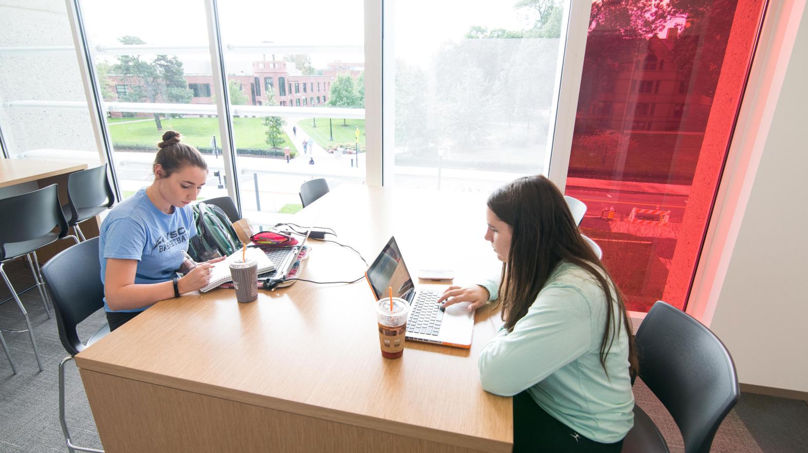 Two female students study at a table in the Learning Commons
