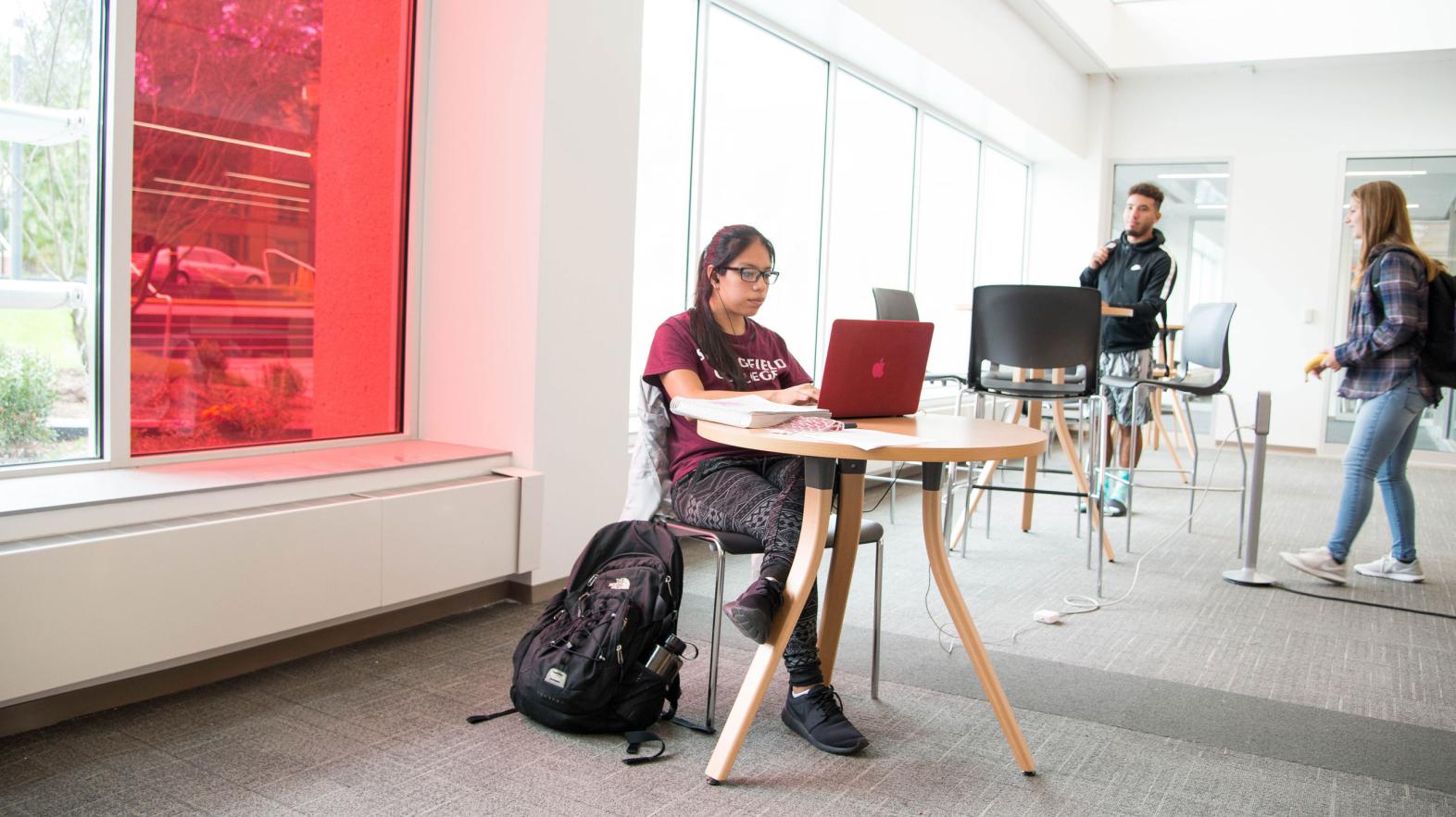 A female student types on her laptop in the Learning Commons.