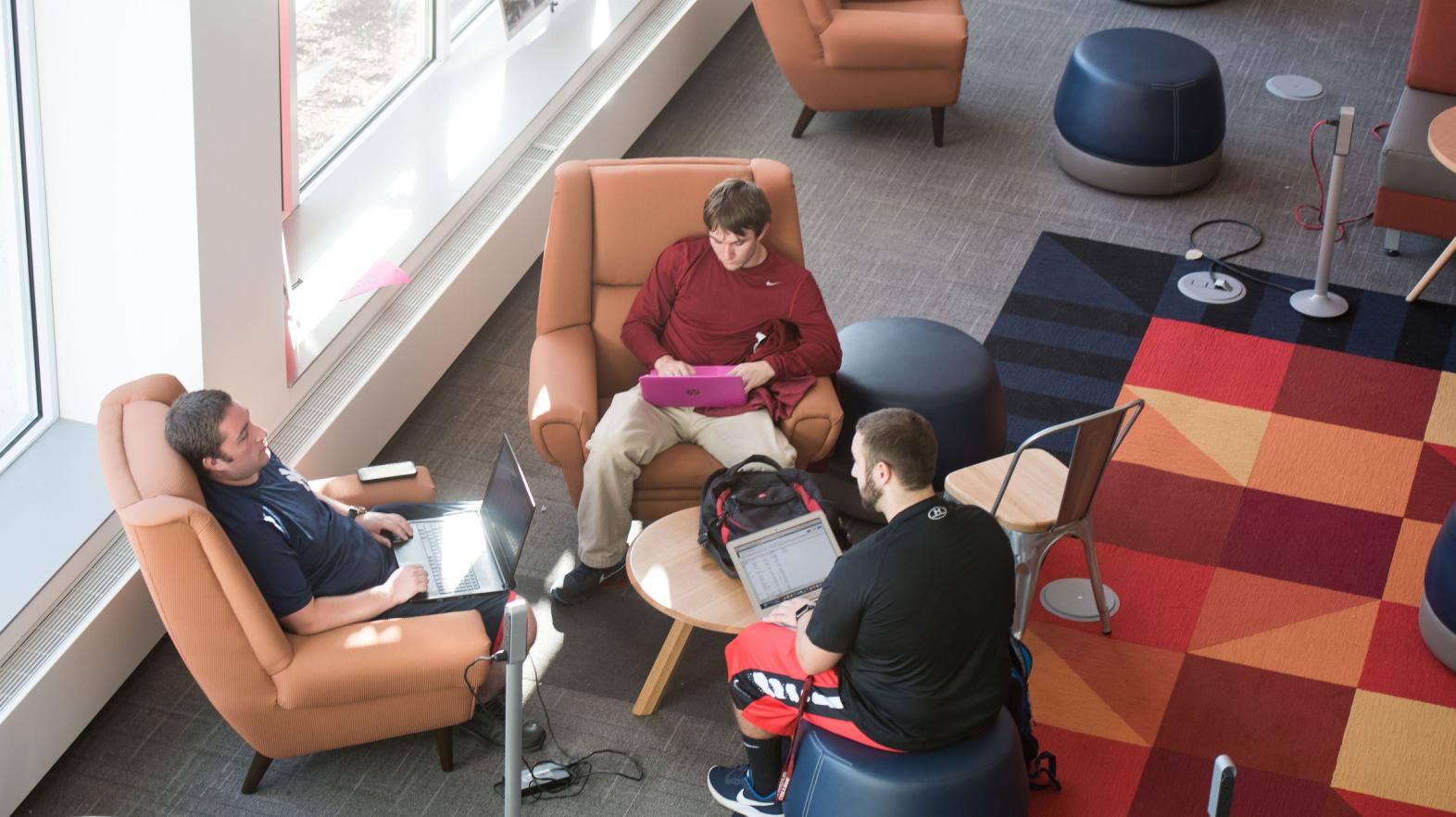 An overhead photo of three male students meeting in the Learning Commons.