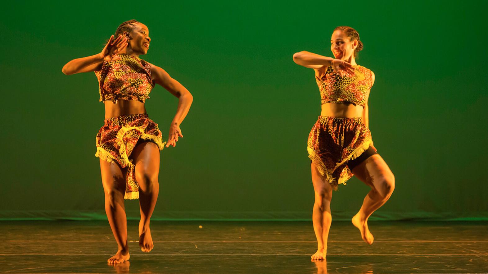 Two dancers perform an African Dance piece on stage