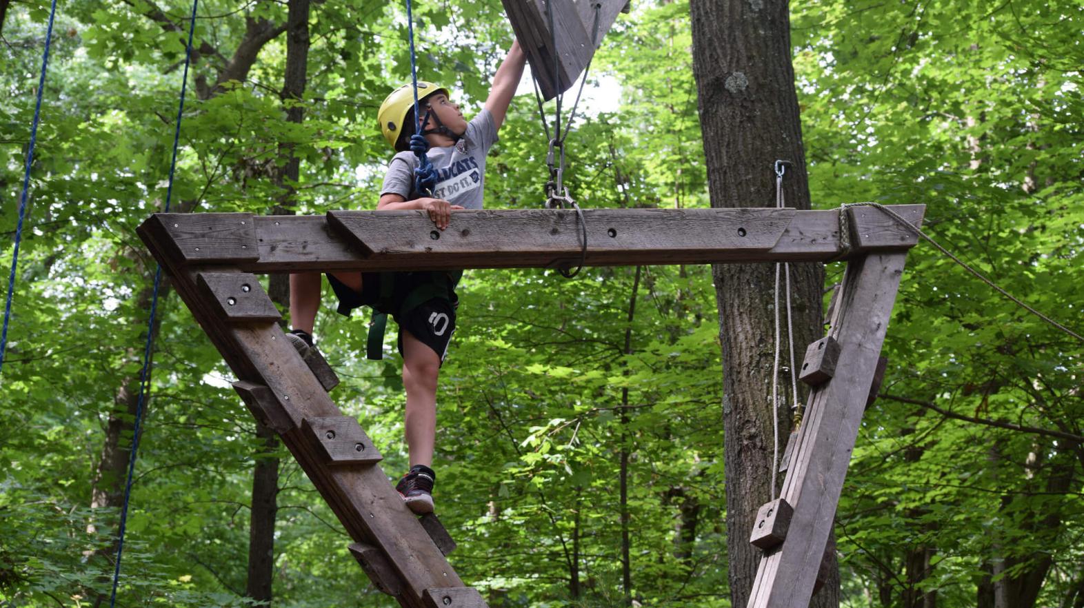 A camper climbs the rope course. 