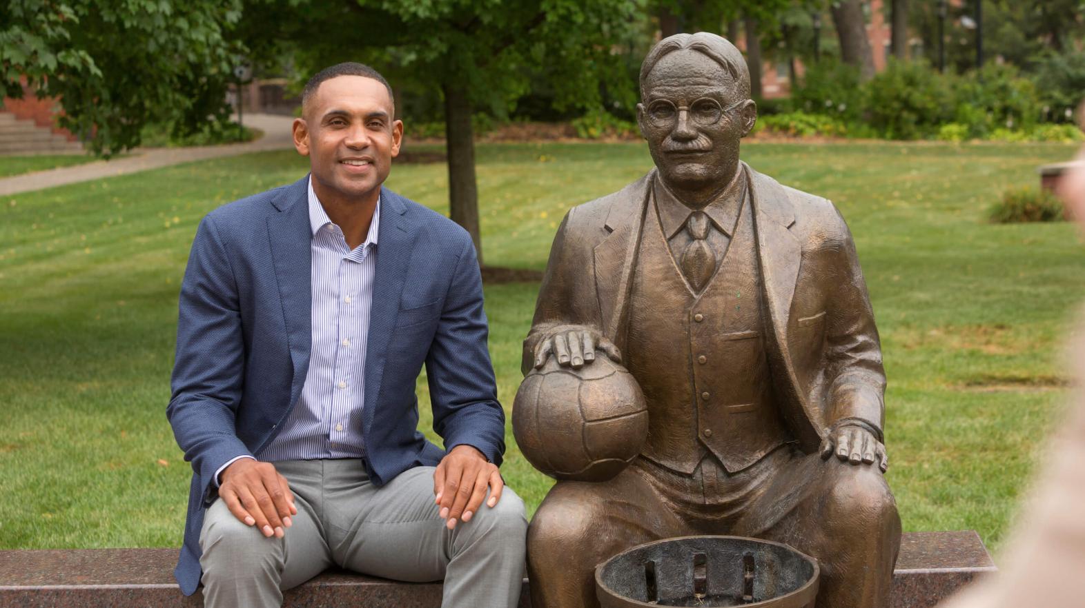Grant Hill sits next to the James Naismith statue. 