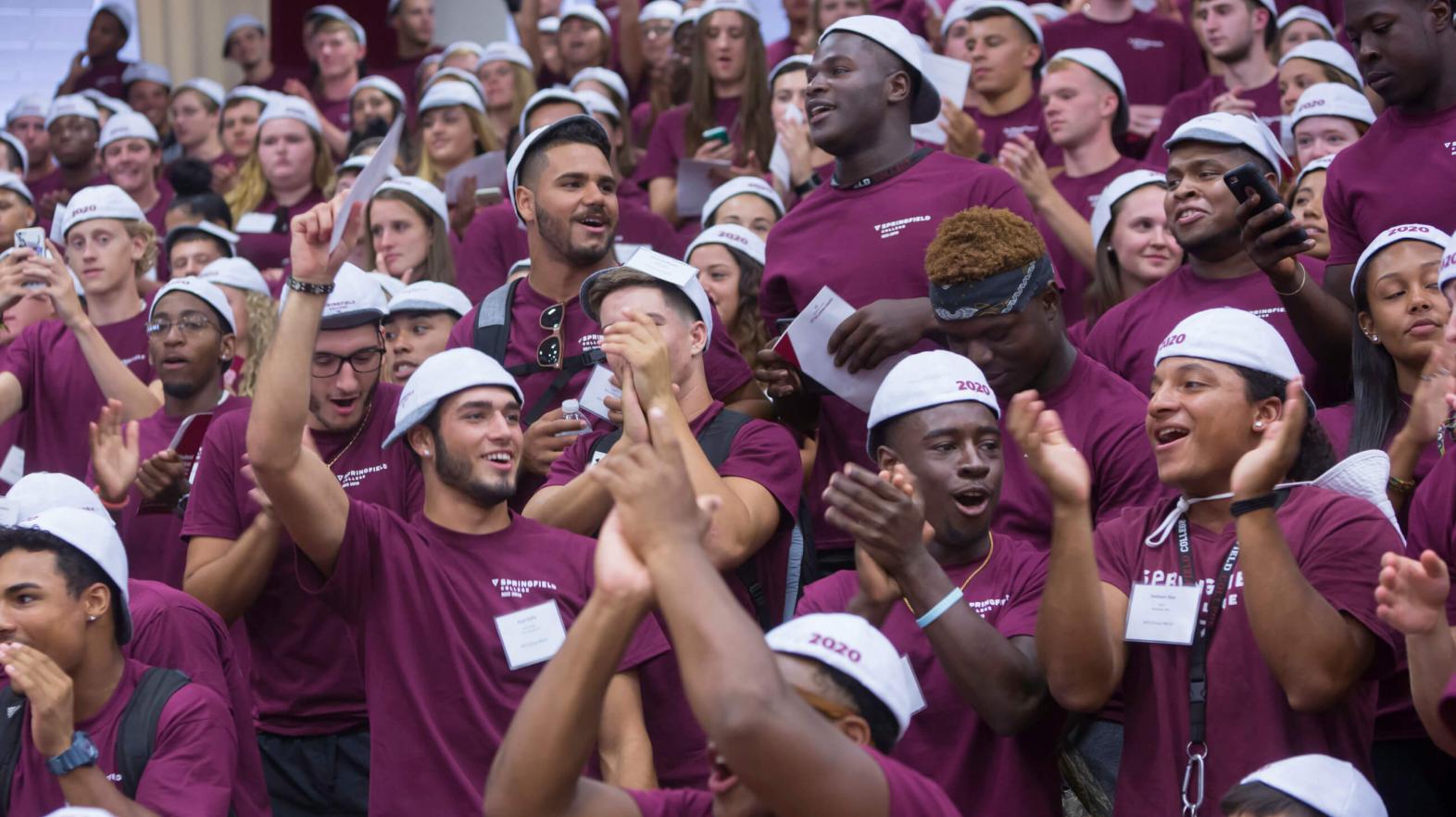 Incoming freshmen cheer in a crowd while wearing their beanies. 