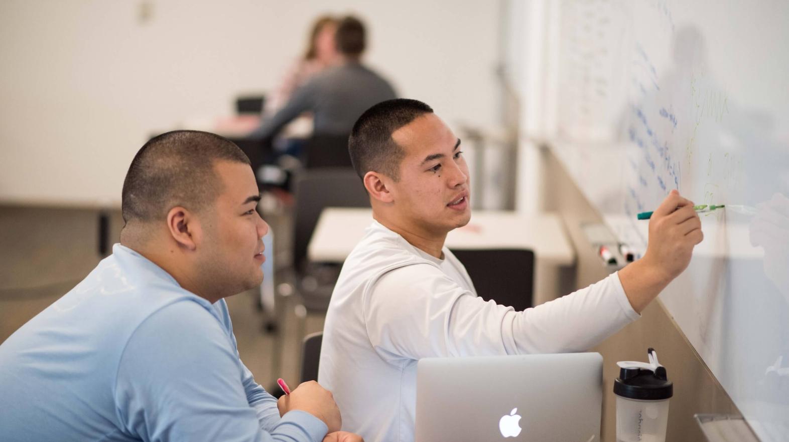 Two students use the white board in the academic success center.