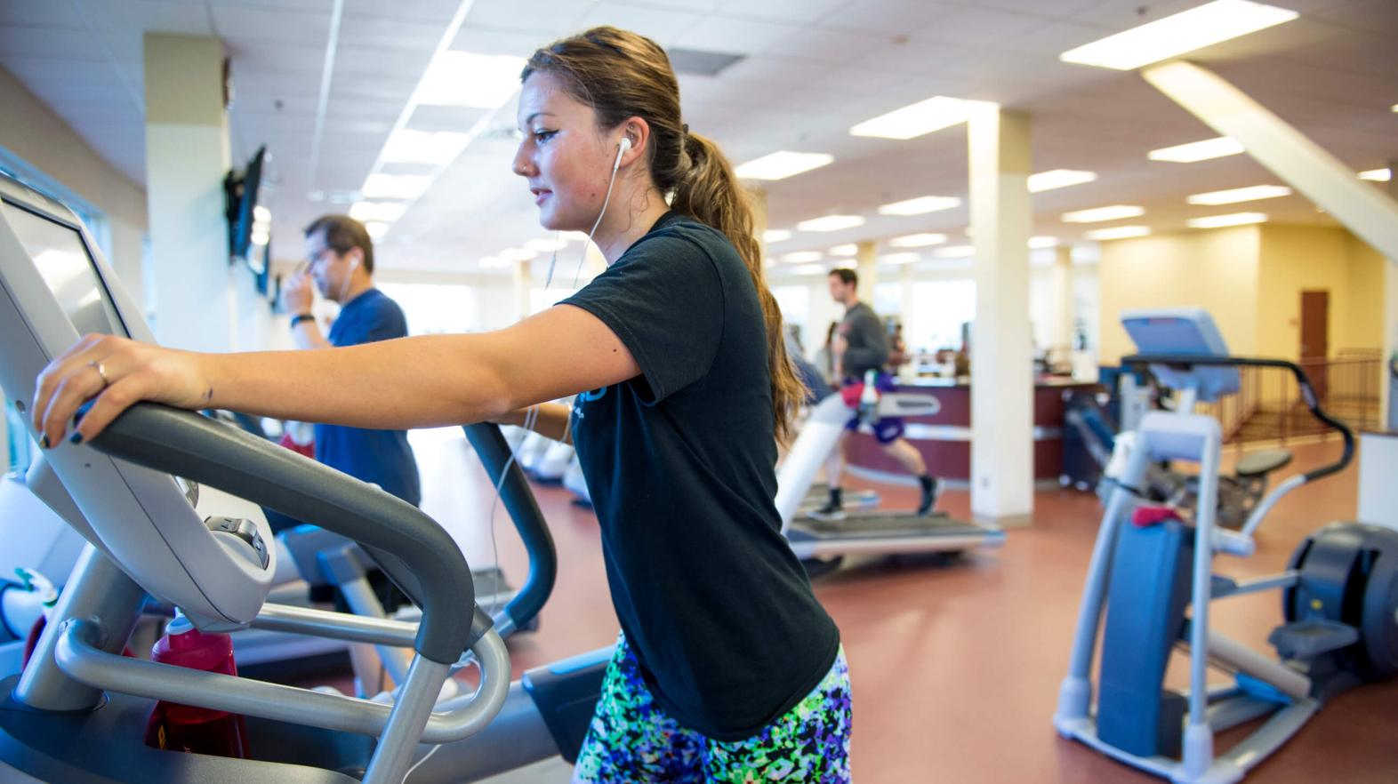 A young woman works out on an elliptical.