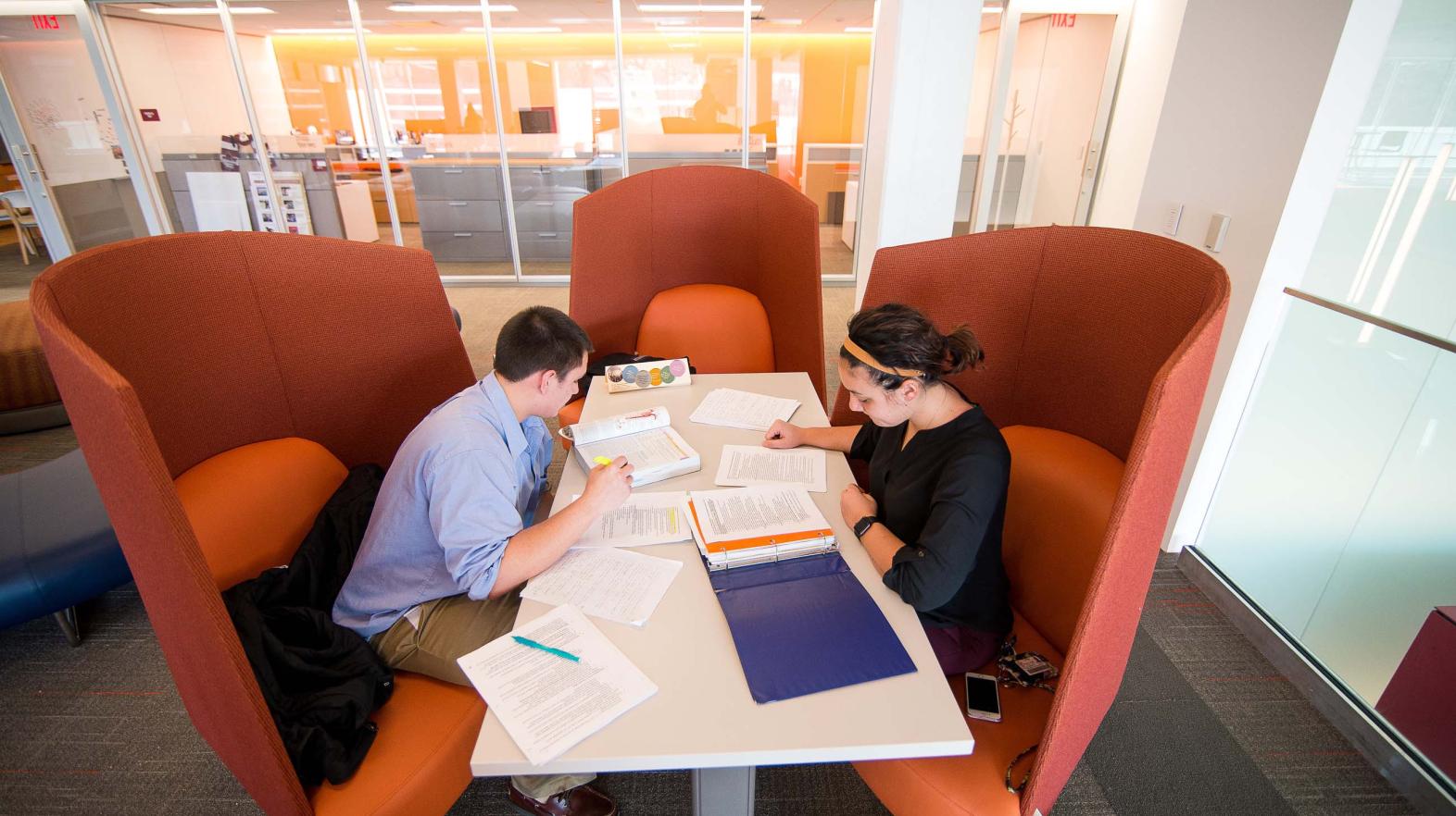 Two students sit at a table in the Learning commons, studying. 