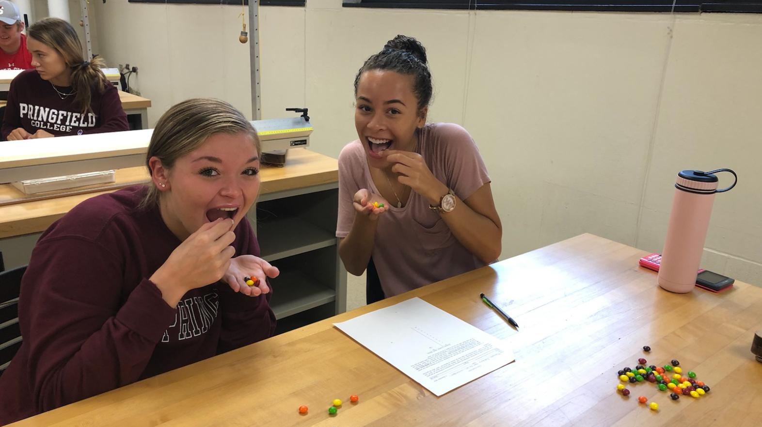 Two female students pretend to eat skittles during a math assignment