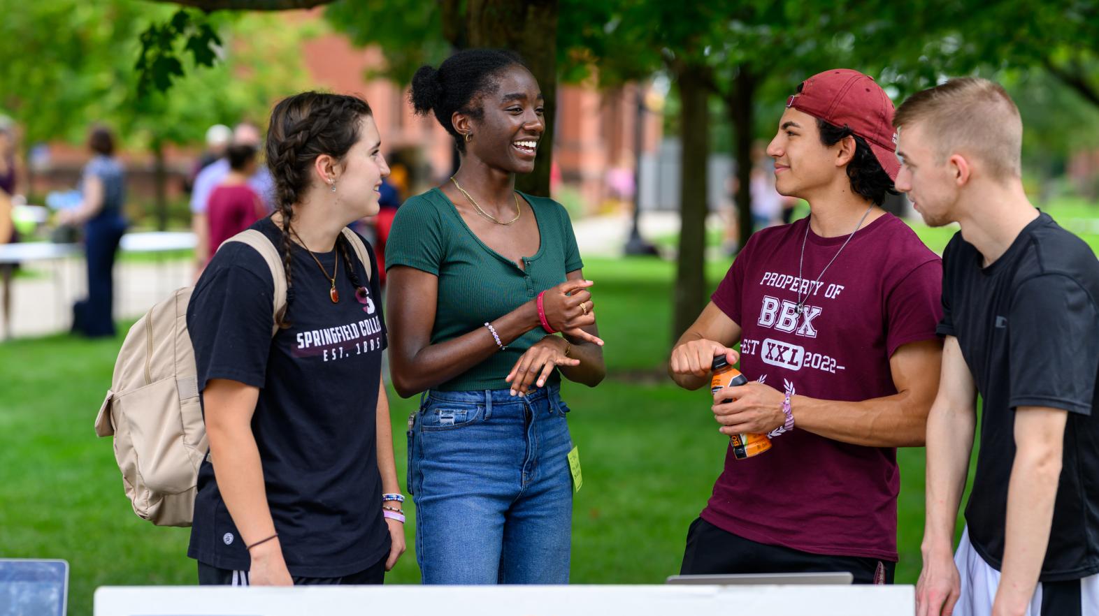 Students at a club fair talking on Naismith green