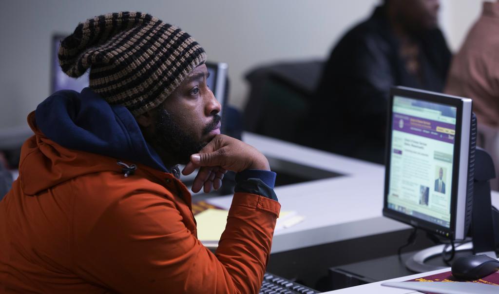 Student sitting at a desktop computer listening to lecture