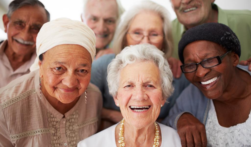 A group of seniors smiling together while in a retirement home.