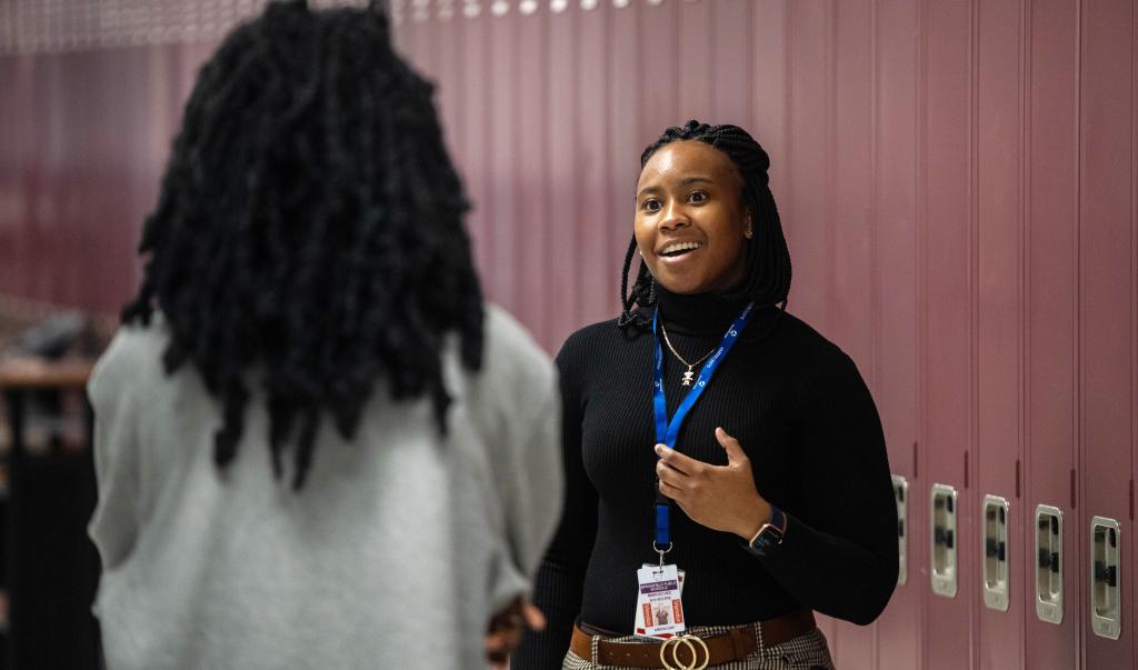 School counselor speaking with student in hallway in front of lockers.