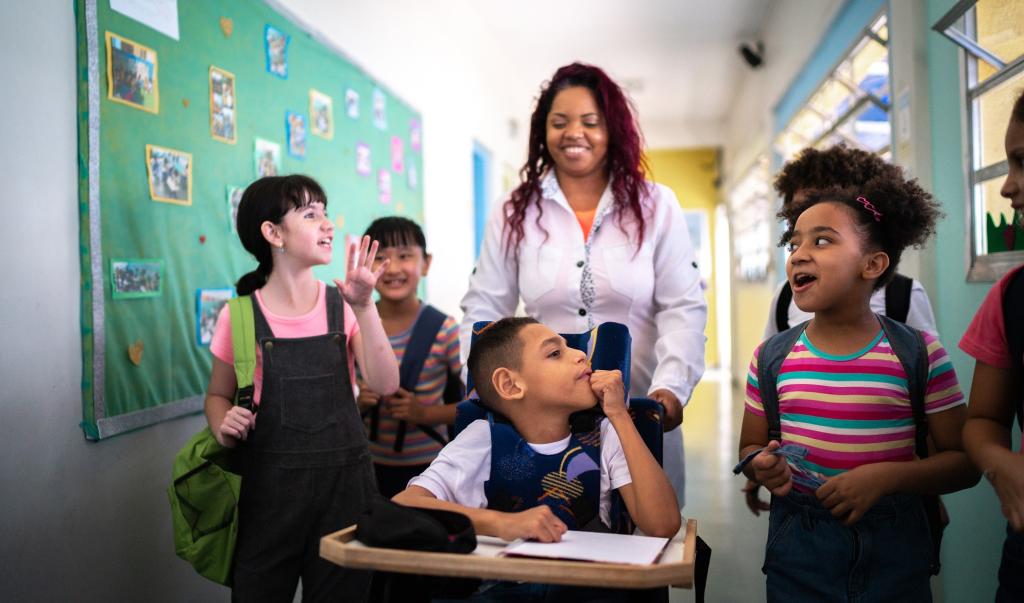 Teacher and students walking in the corridor at school - including a person with special needs