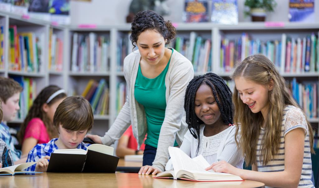 Elementary students working with teacher in library