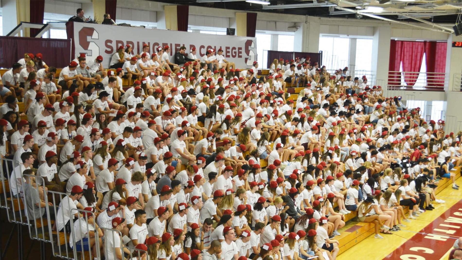 New students sit in the bleachers wearing beanies for their convocation.