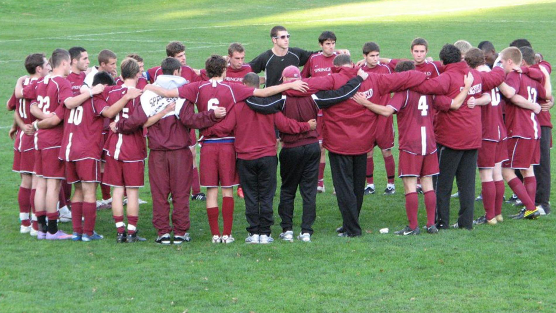 Soccer team huddled on the field. 