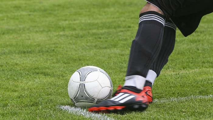 a male soccer player's foot sttriking the ball